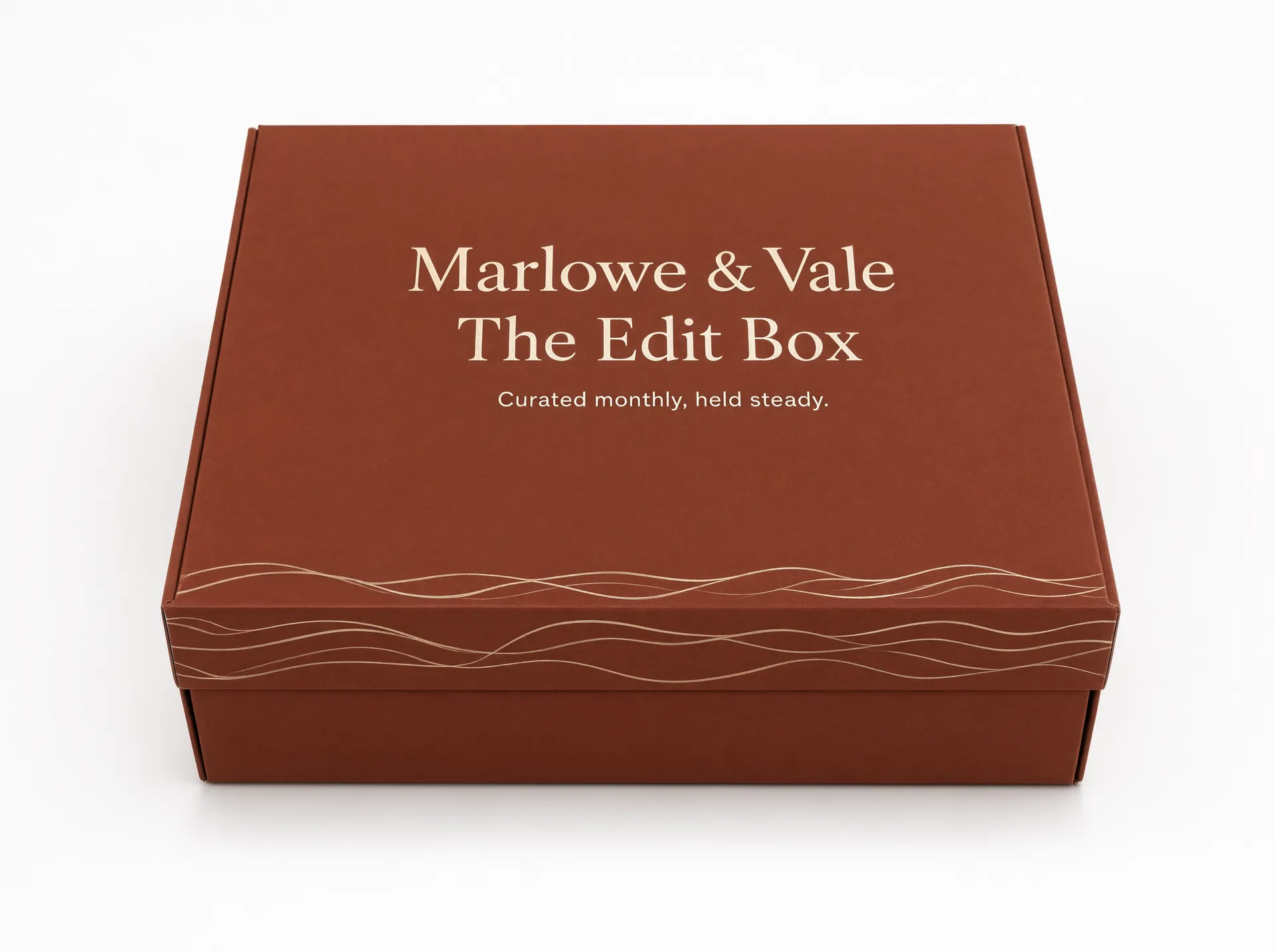 Closed terracotta rigid subscription box with a cream wave-line motif on the lid
