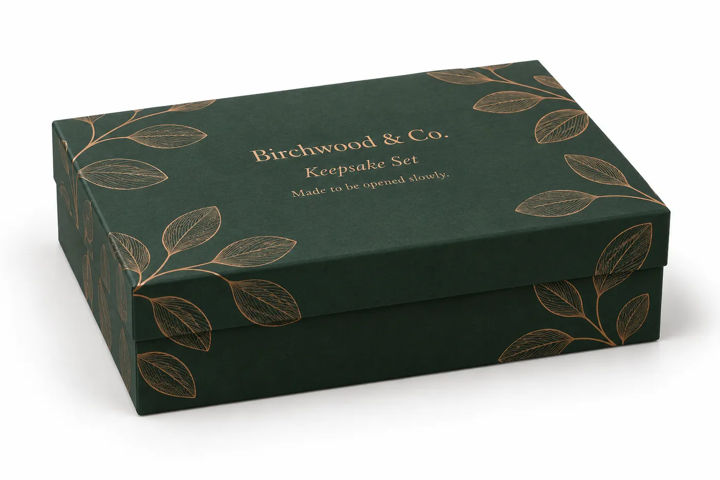 Closed forest-green rigid gift box with a copper foil leaf motif and Birchwood & Co. lid mockup